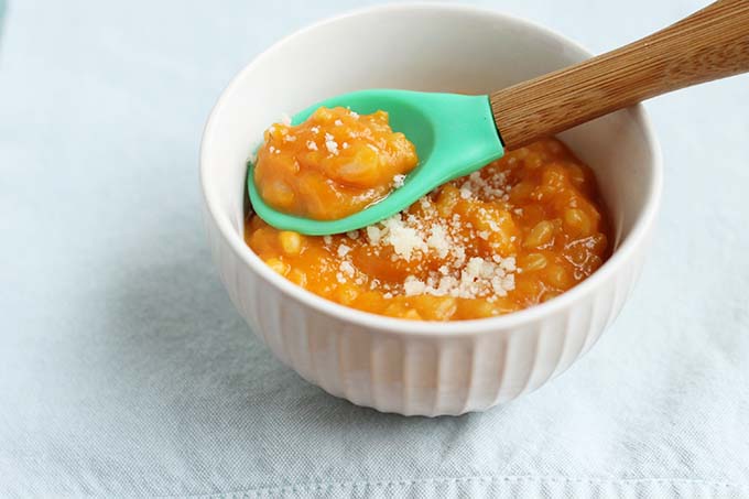 butternut squash risotto for babies in small white bowl and bamboo spoon