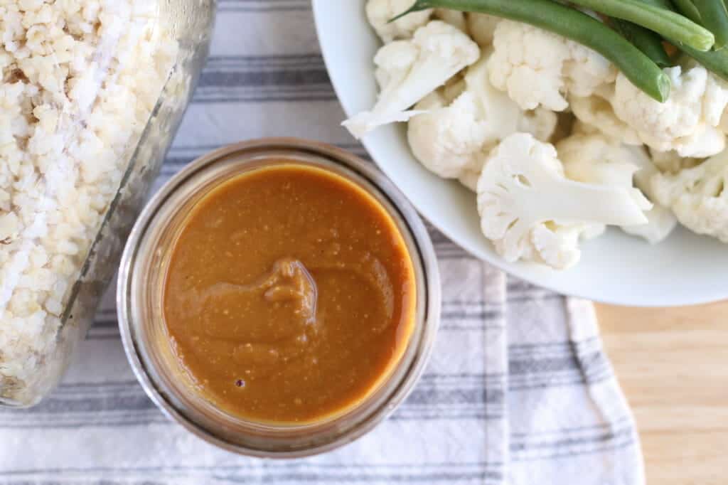 easy peanut sauce in jar with vegetables and rice on tea towel