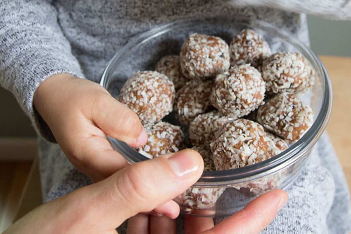 no-bake energy bites with mom and kids hand