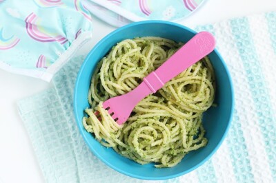 broccoli pesto on spaghetti in blue bowl with pink fork