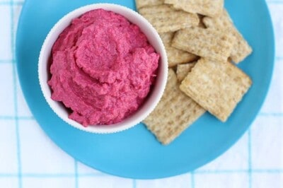 beet hummus on blue plate with crackers