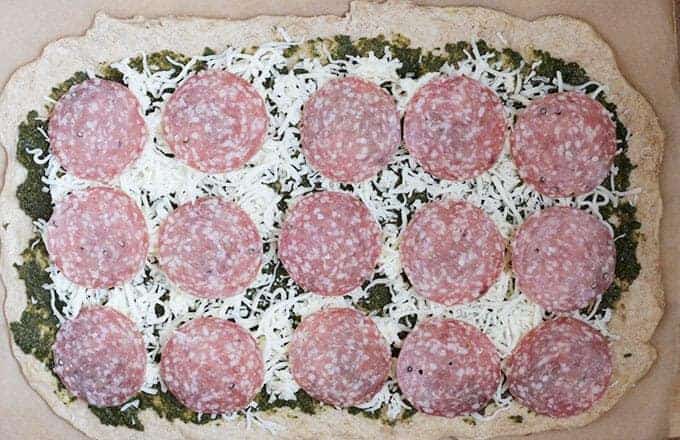 pizza dough spread with pesto, cheese and salami
