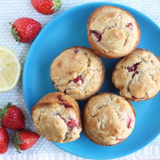 strawberry muffins on blue plate with fresh berries and lemon half