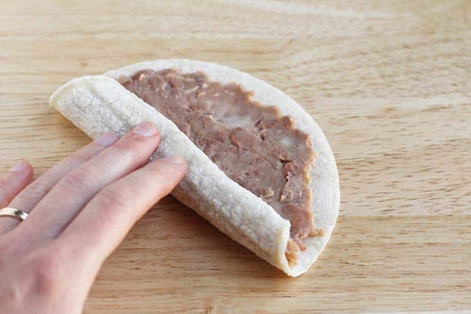 rolling up bean taco with woman's hand