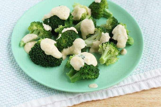 broccoli and cheese sauce on green plate on blue towel