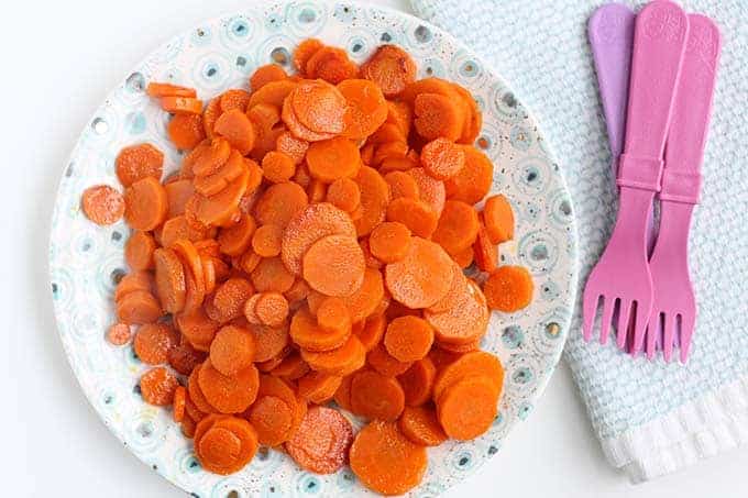 sauteed carrots cut in rounds on a plate with pink forks