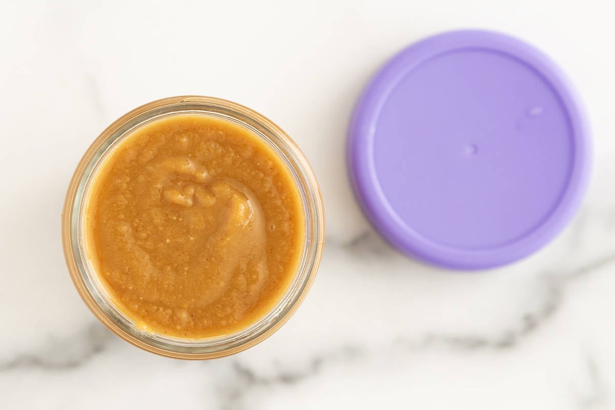 Peanut sauce in storage container with purple lid.