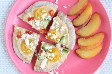 greek pita pizzas on pink plate with peaches