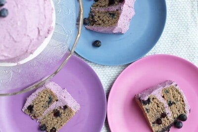 sliced blueberry birthday cake on colored plates.