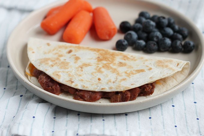 bean and cheese quesadilla on plate with berries and carrots