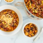 Veggie chili in pot and two bowls with cheese.