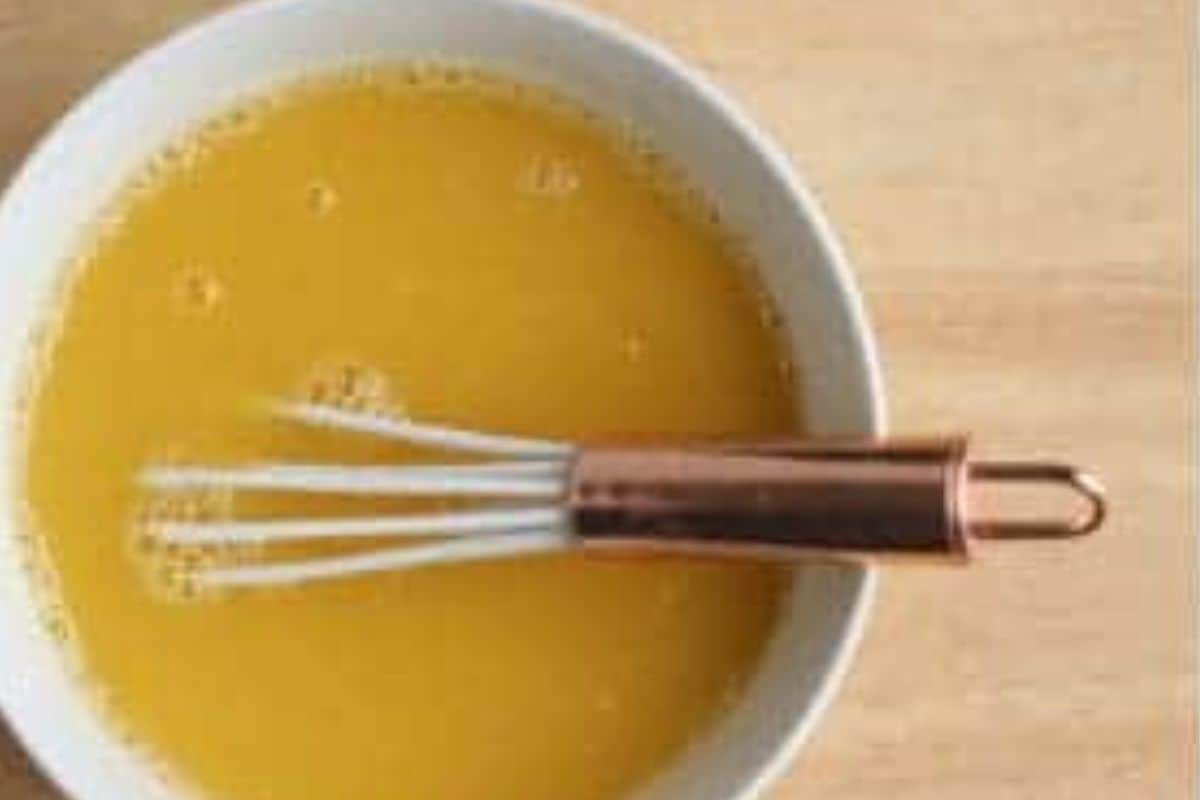 Mixture for orange honey fruit snacks in pot with whisk.