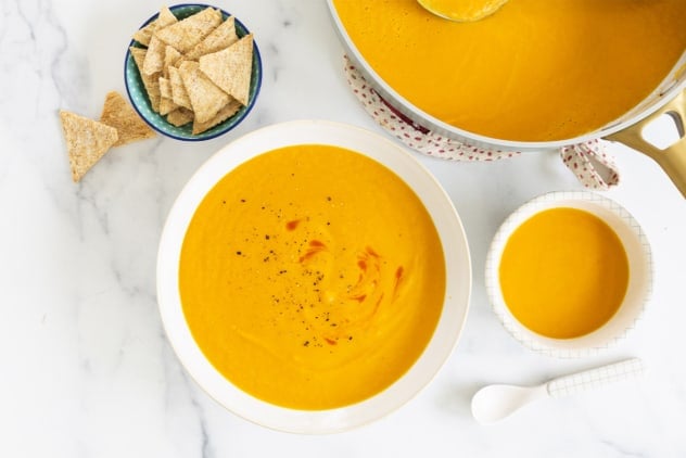 Carrot soup in various bowls and pan.