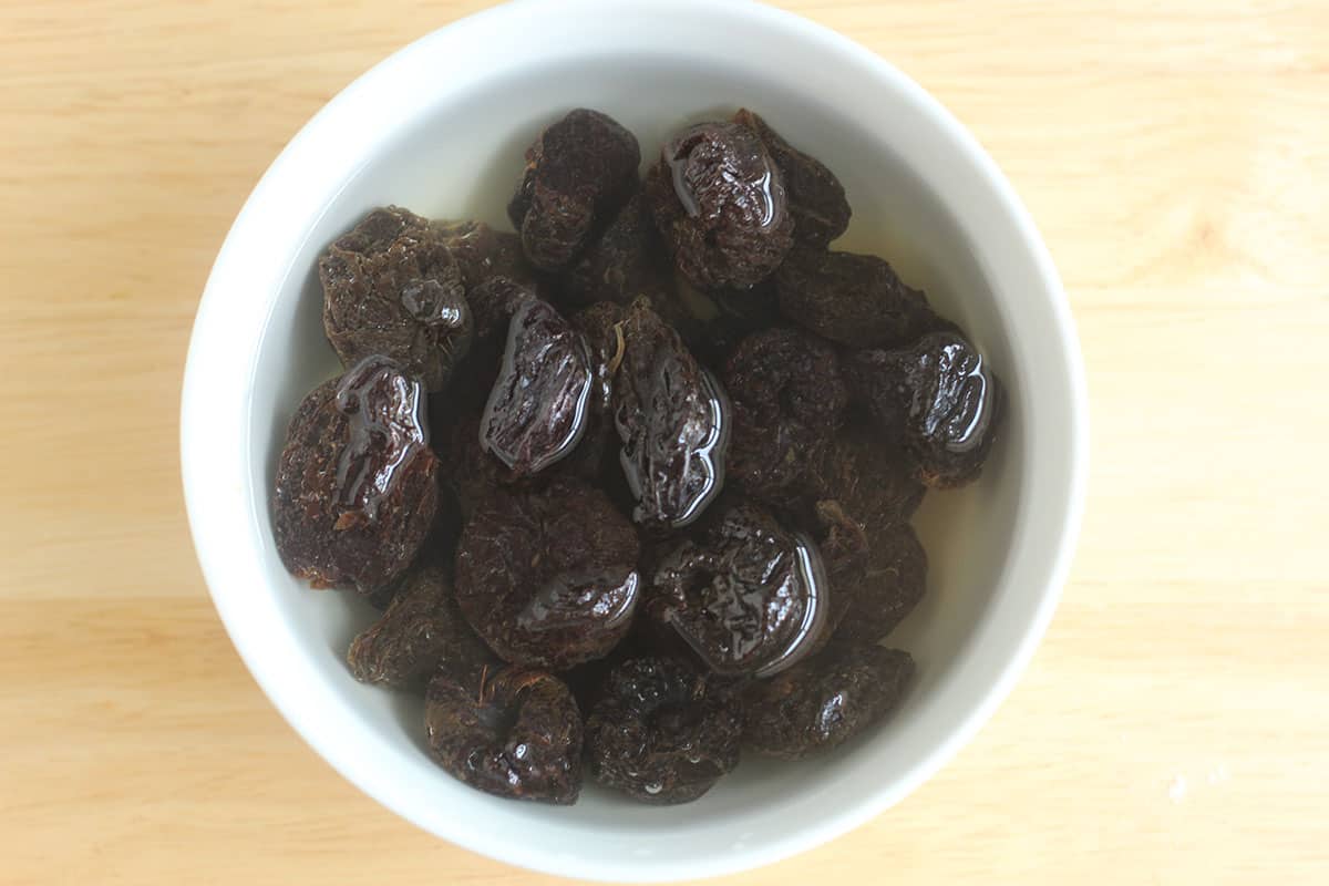prunes in white bowl of water.