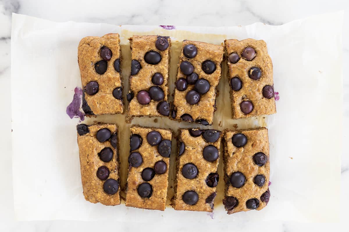 Blueberry date bars cut into slices on parchment paper.