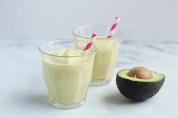 avocado mango smoothies on counter with straws.