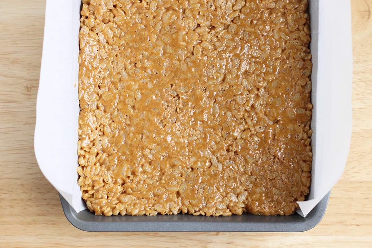 Peanut butter crispy rice mixture pressed into a baking pan.