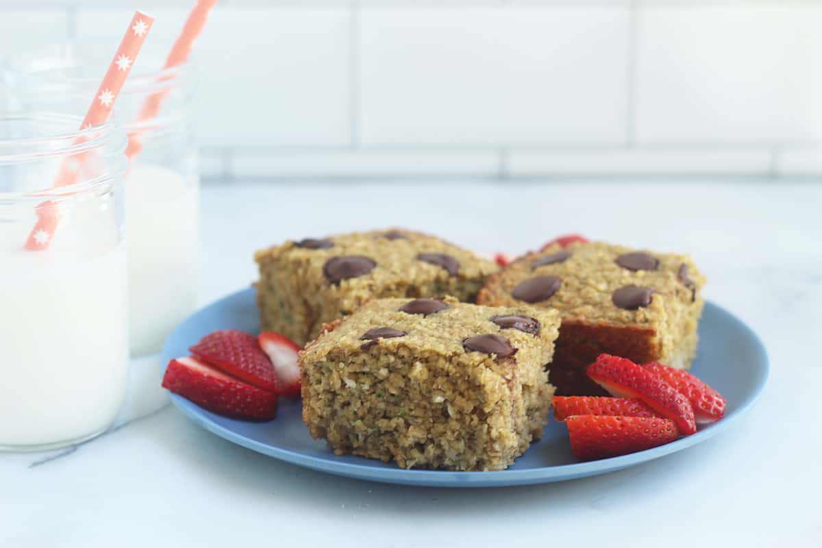 zucchini banana bread squares on plate with milk cups