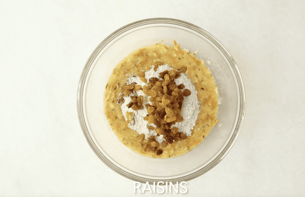 Adding raisins to batter for zucchini carrot muffins.