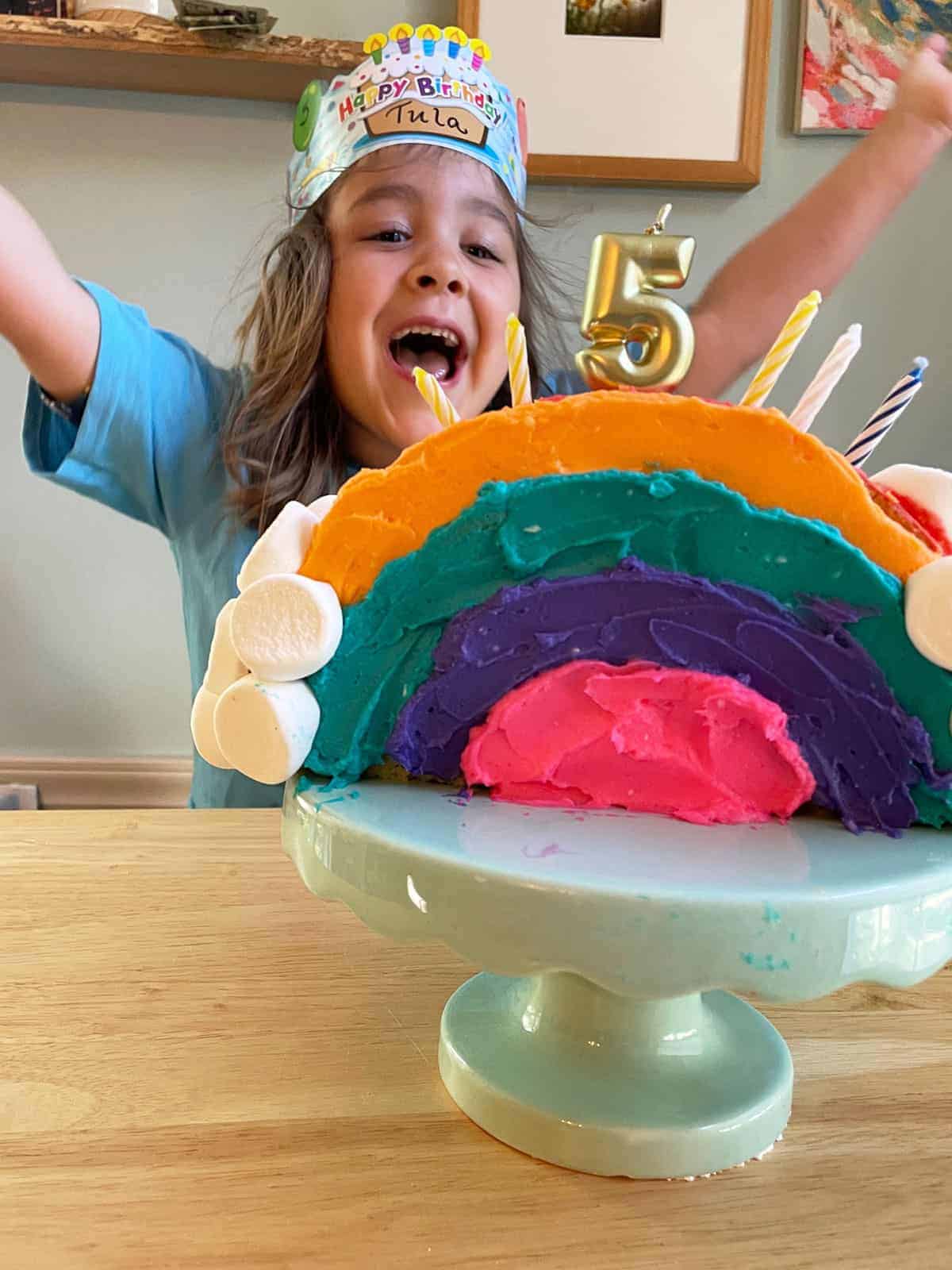 child with rainbow birthday cake