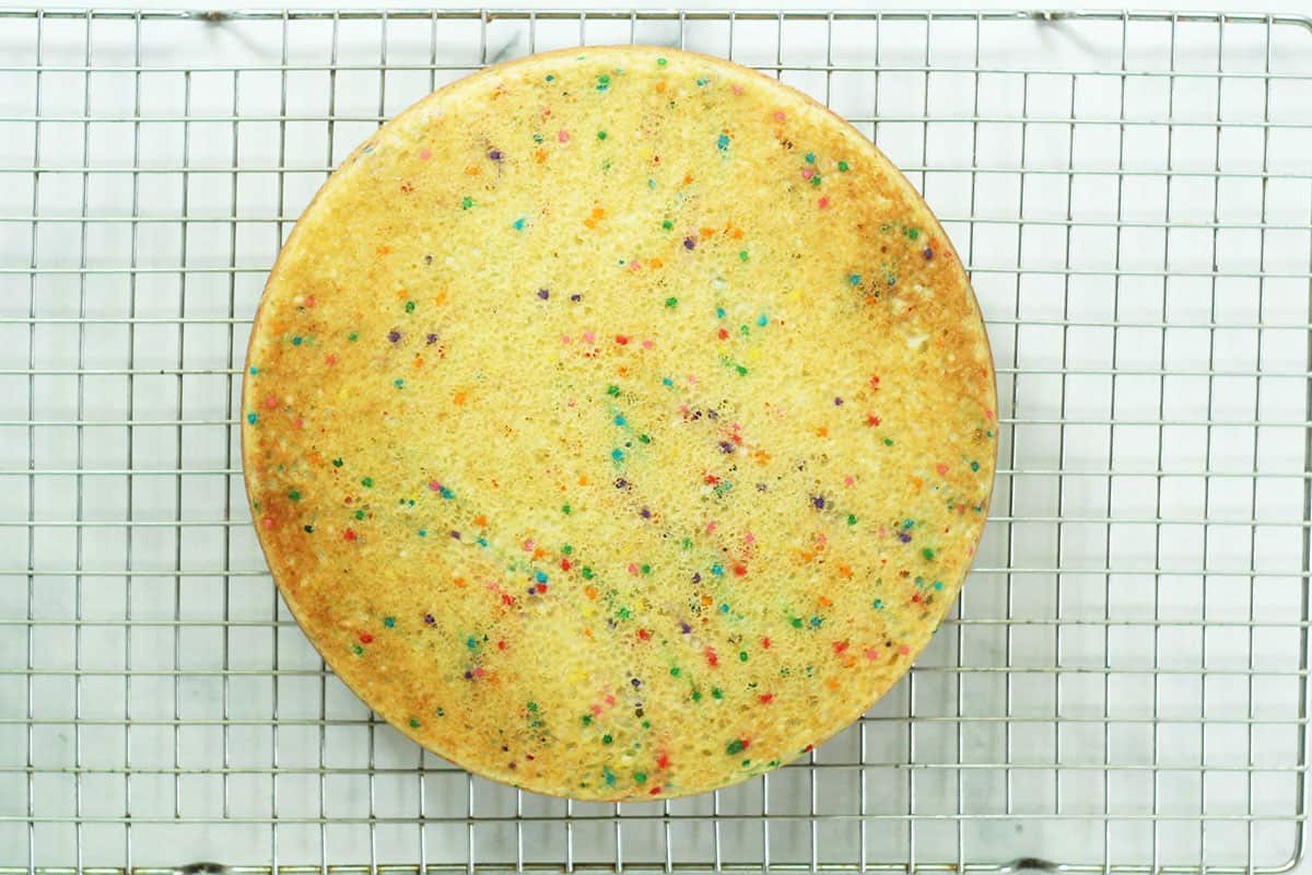 cooling rainbow cake on wire rack.