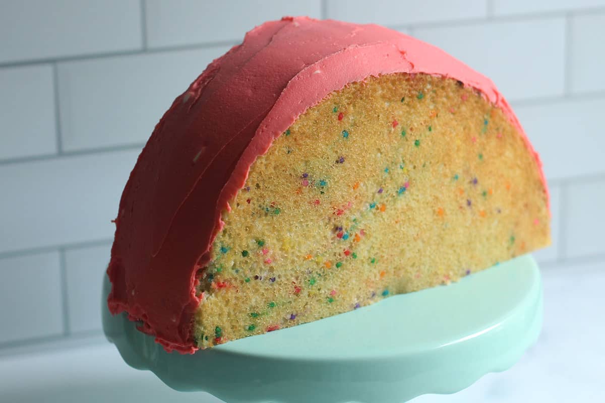 assembling the rainbow cake with pink frosting.