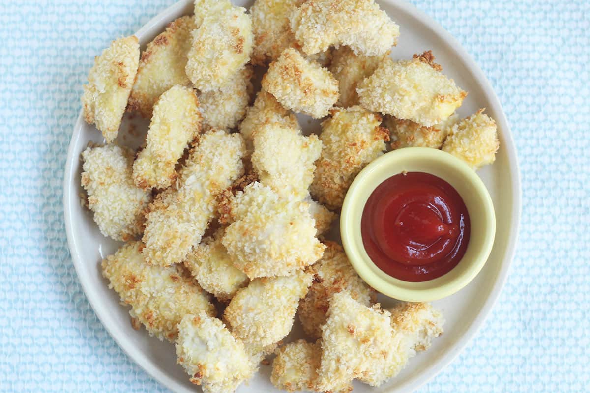 baked chicken nuggets on plate with ketchup.