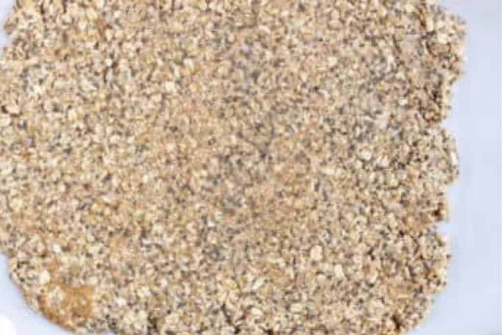 Homemade granola bars mixture spread out on parchment paper.