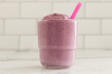 blueberry pregnancy smoothie in glass with pink straw.