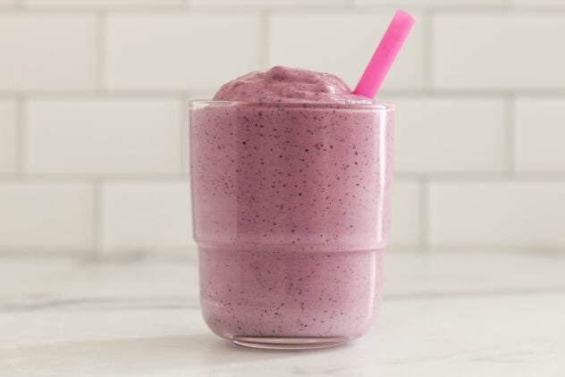 blueberry pregnancy smoothie in glass with pink straw.