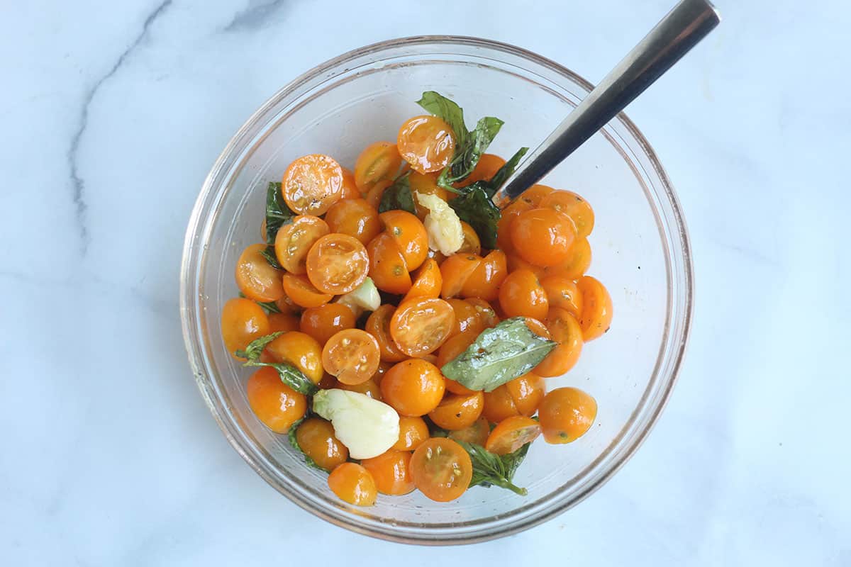 marinated cherry tomato sauce ingredients in glass bowl.