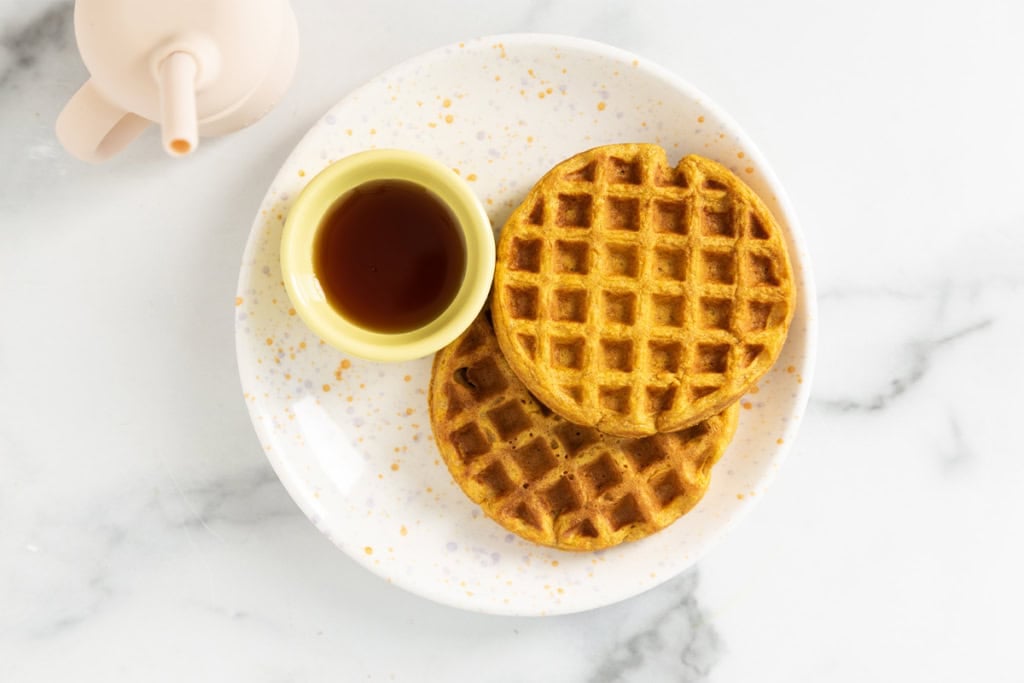 sweet potato waffle with syrup on white plate.