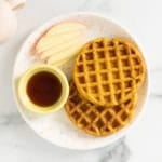 Sweet potato waffle on white plate with apple slices.