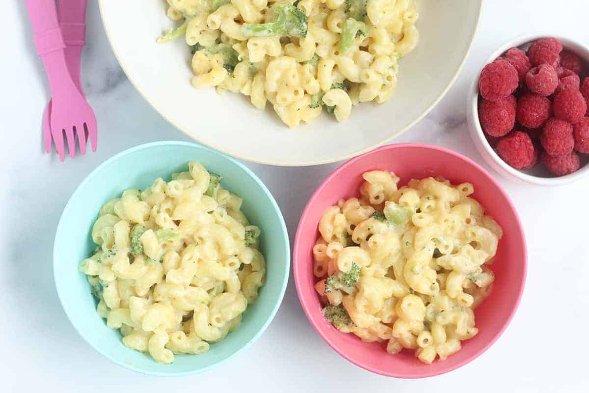 broccoli mac and cheese in white and colorful bowls