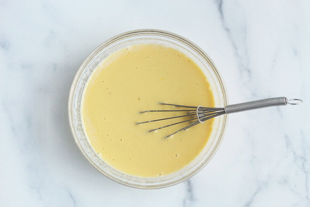 Batter for birthday cake muffins in glass bowl with whisk. 
