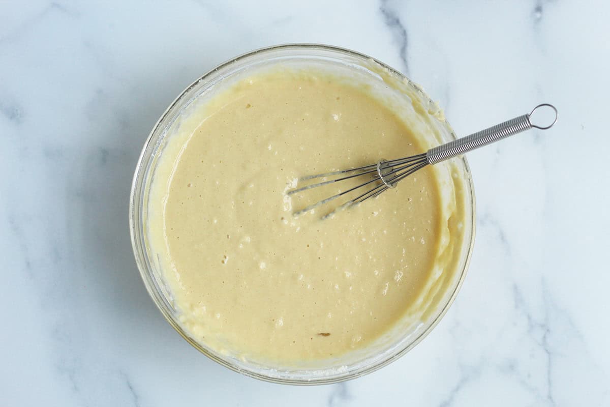Batter for birthday cake muffins in glass bowl with whisk.