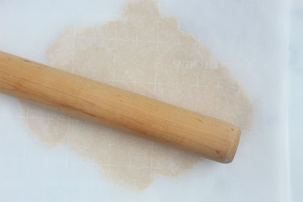 Rolling out christmas cookie dough with rolling pin.