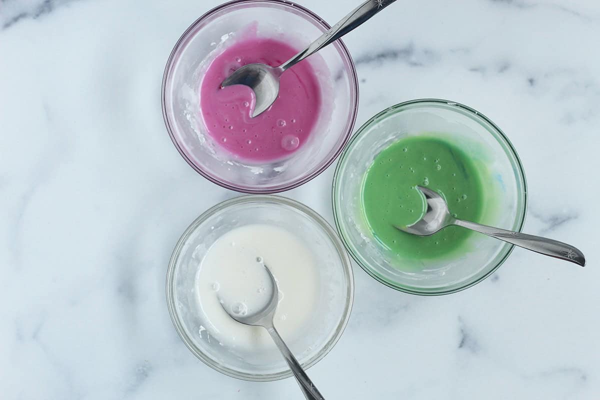 Frosting for christmas cookies in three glass bowls.