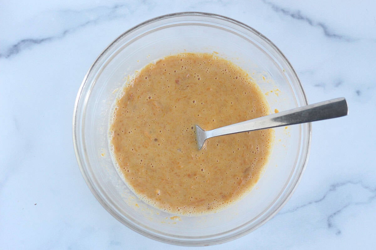 Batter for sweet potato donuts in glass bowl with spoon.