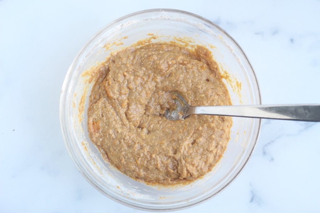 Batter for sweet potato donuts in glass bowl with spoon.