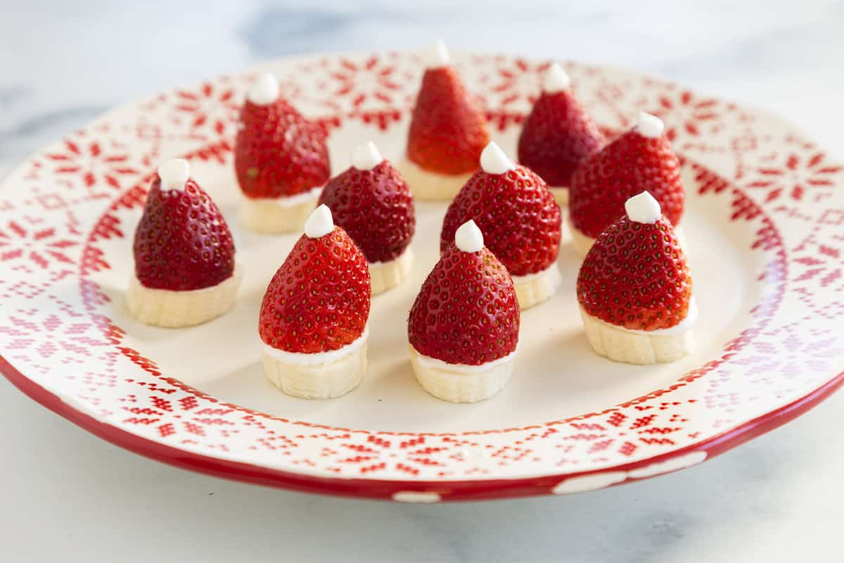 Strawberry santas on red and white christmas plate.