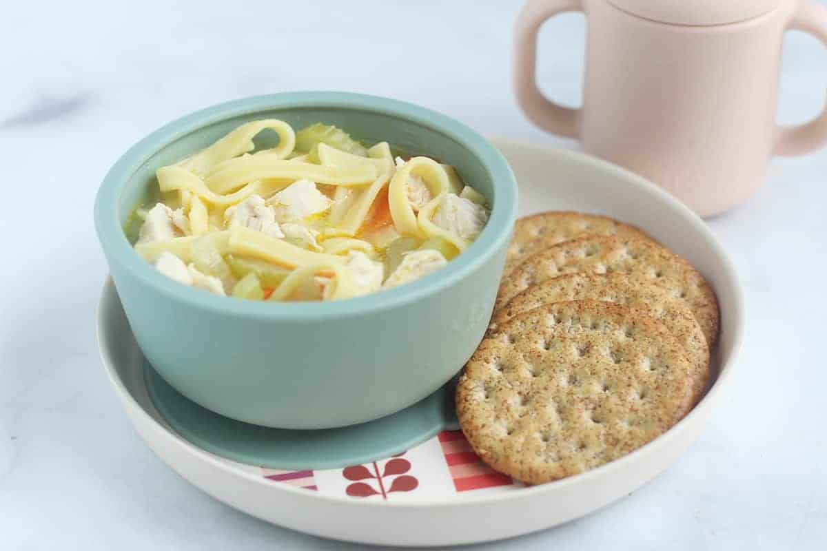 chicken noodle soup in bowl with crackers