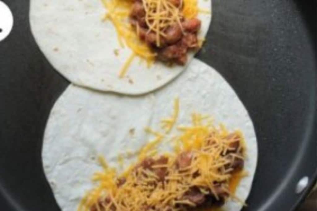Vegetarian quesadillas in pan before folding together.