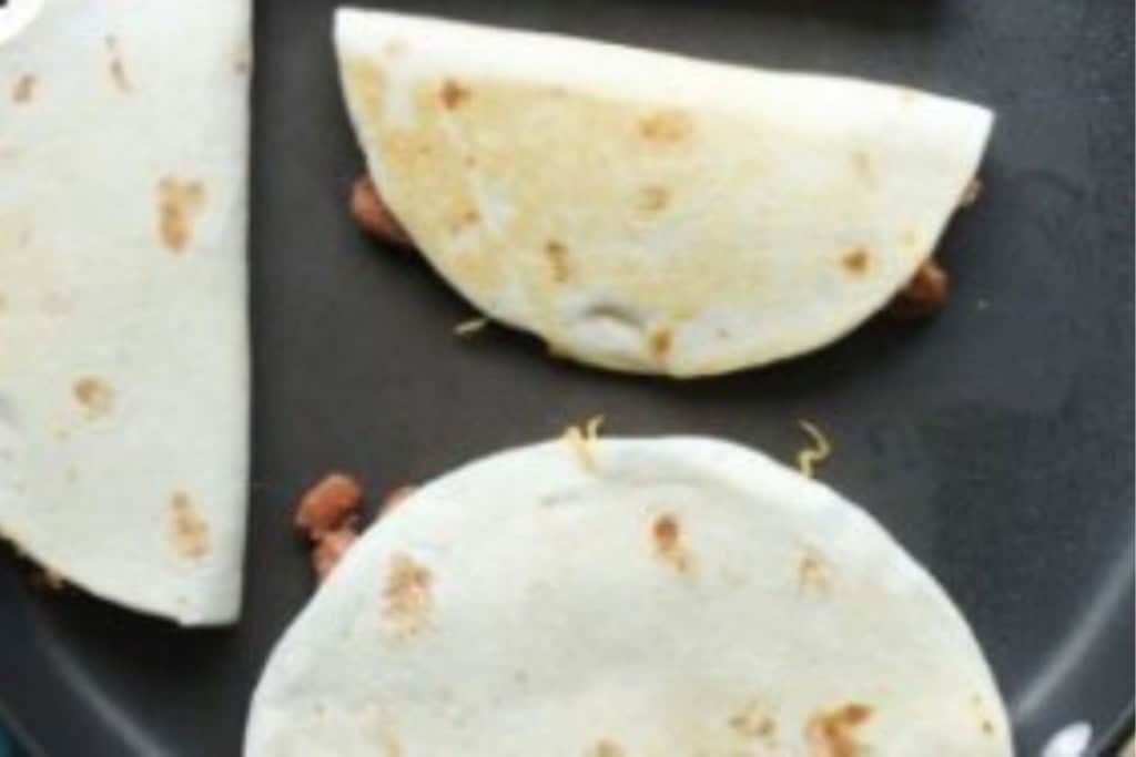 Vegetarian quesadillas in pan after flipping.