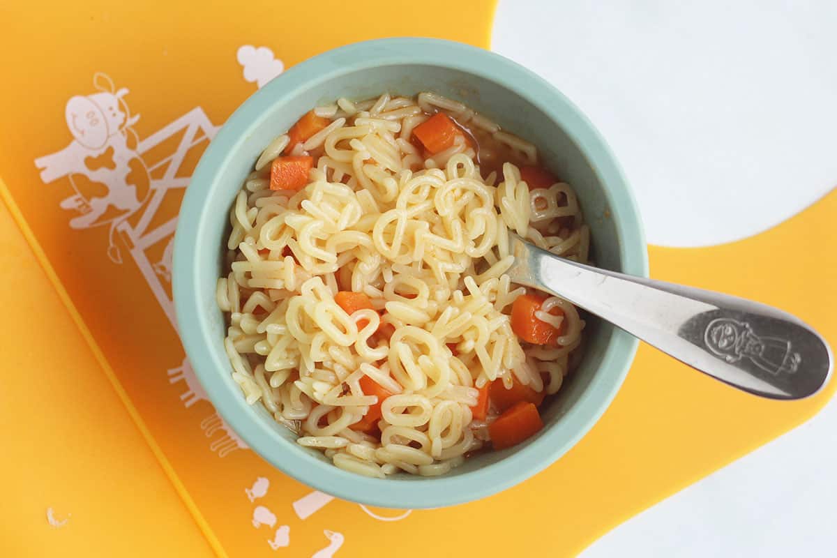 alphabet soup in blue bowl on yellow bib.