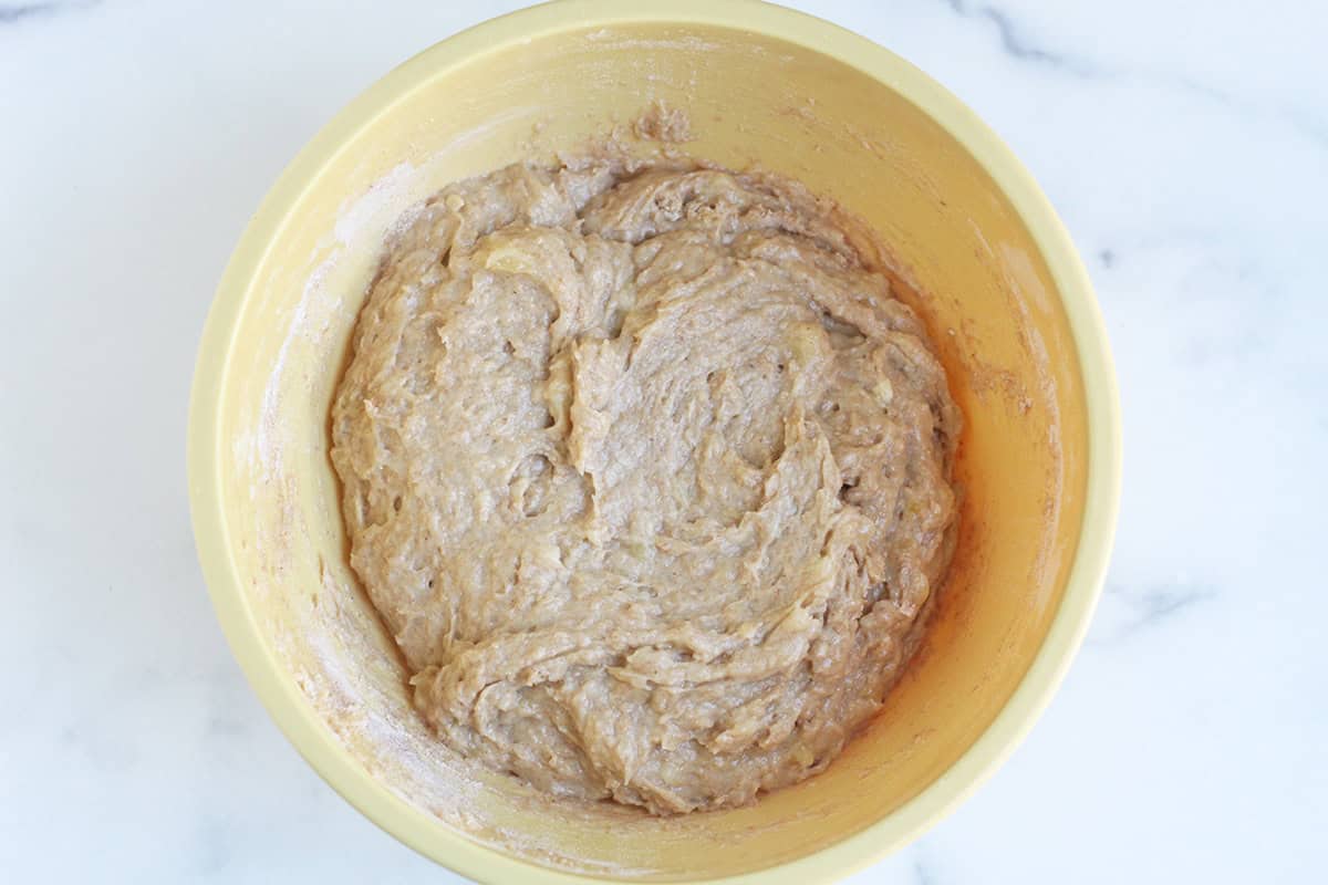 wet and dry ingredients for banana bread muffins in yellow bowl.