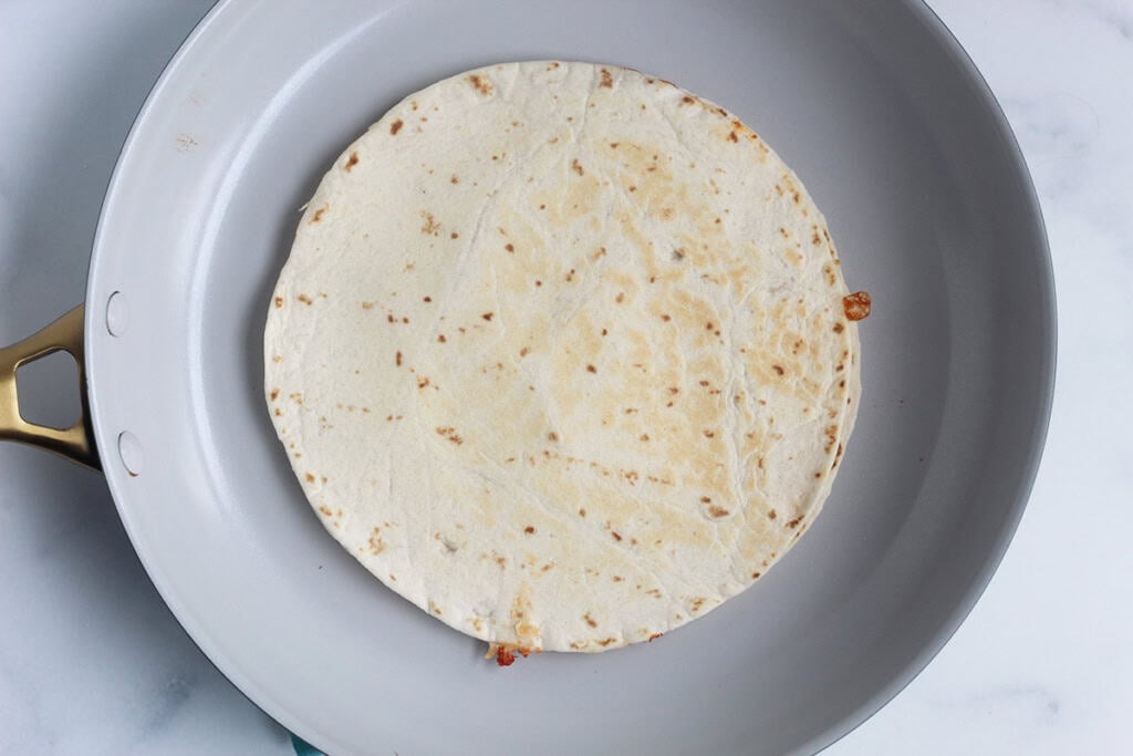 Pizza quesadilla in pan before flipping.