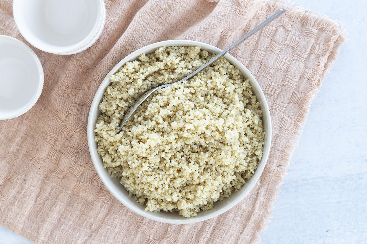 quinoa in white bowl with spoon on towel
