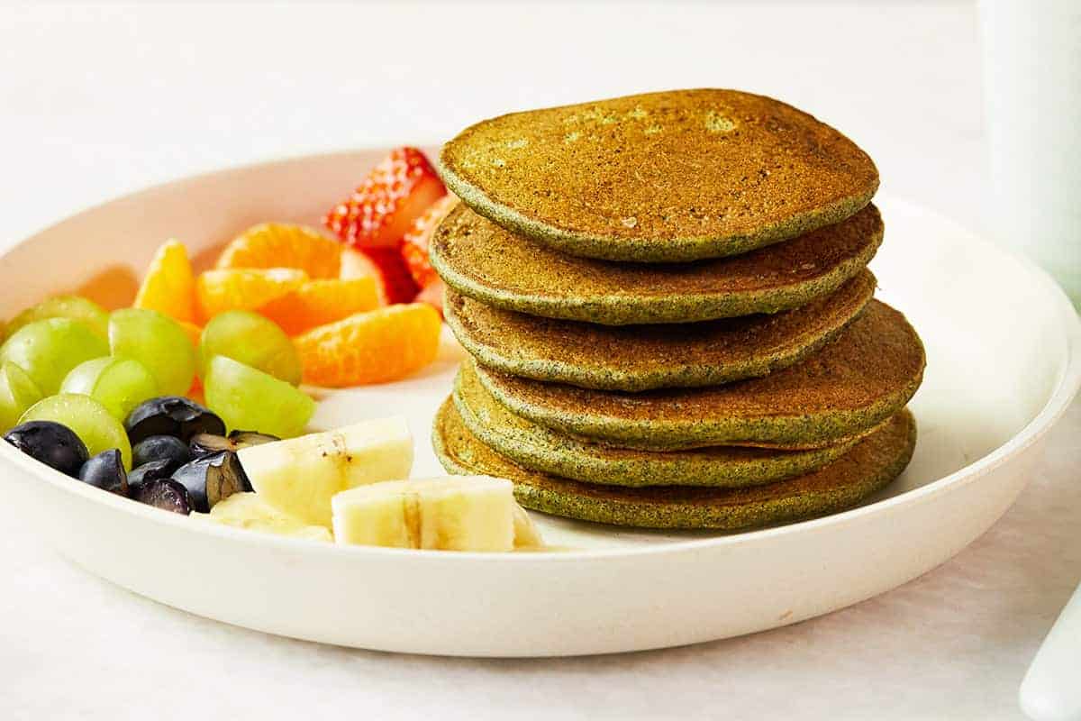 spinach pancakes on white plate with fruit