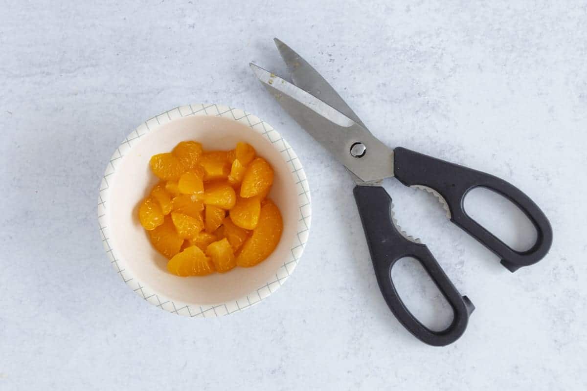 cut up canned oranges with kitchen scissors